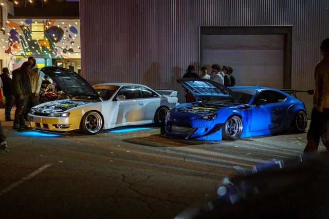 Two modified Japanese performance cars displayed at a nighttime car meet